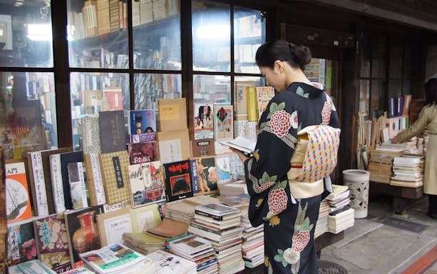 Woman in kimono browsing books at a Kyoto street market during a guided bike tour.