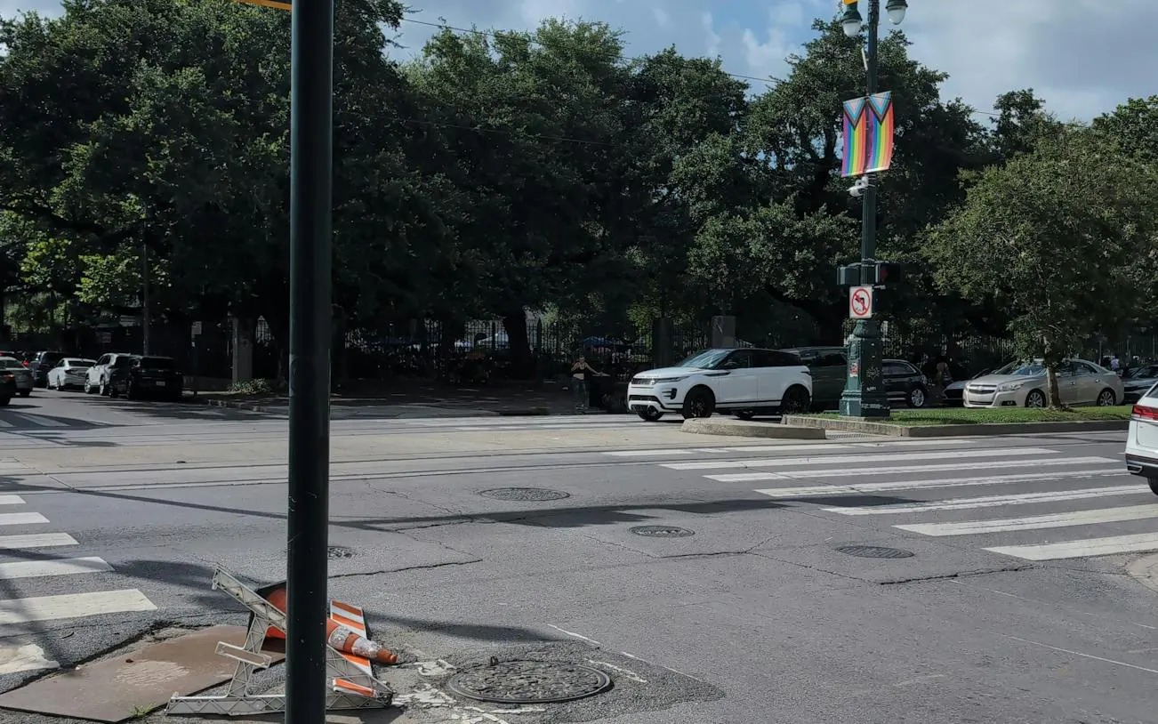 Street intersection in New Orleans with parked cars and a colorful banner on a lamppost.