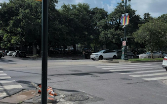 Street intersection in New Orleans with parked cars and a colorful banner on a lamppost.