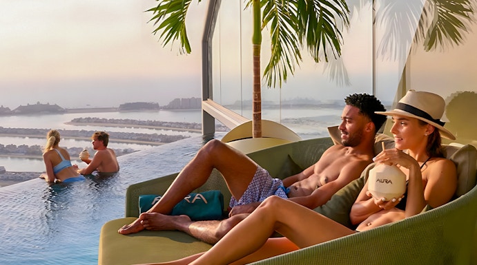 Couples relaxing at AURA Sky Pool, Dubai, with sunrise view over the city.