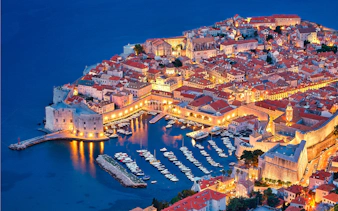 Aerial view of Dubrovnik's illuminated Old Town and harbor at night, Croatia.