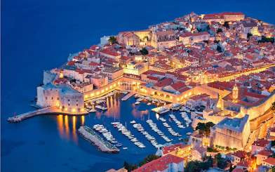 Aerial view of Dubrovnik's illuminated Old Town and harbor at night, Croatia.