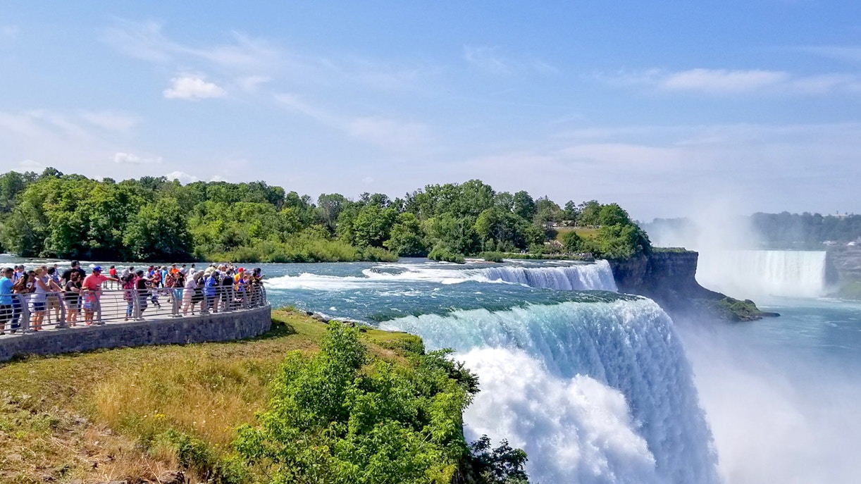 Tourists on Luna Island view Niagara Gorge and waterfalls through mist.