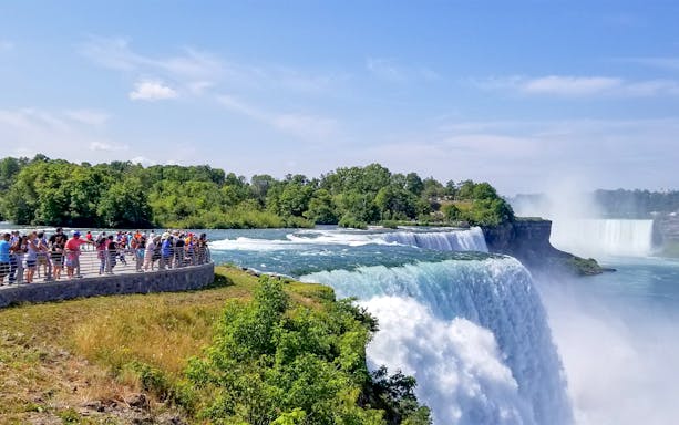 Tourists on Luna Island view Niagara Gorge and waterfalls through mist.