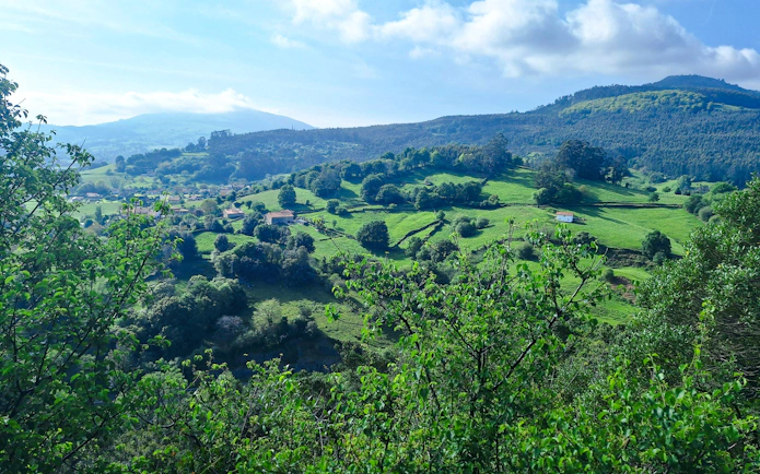 Valley landscape near the Caves of Monte Castillo with green hills and scattered houses.