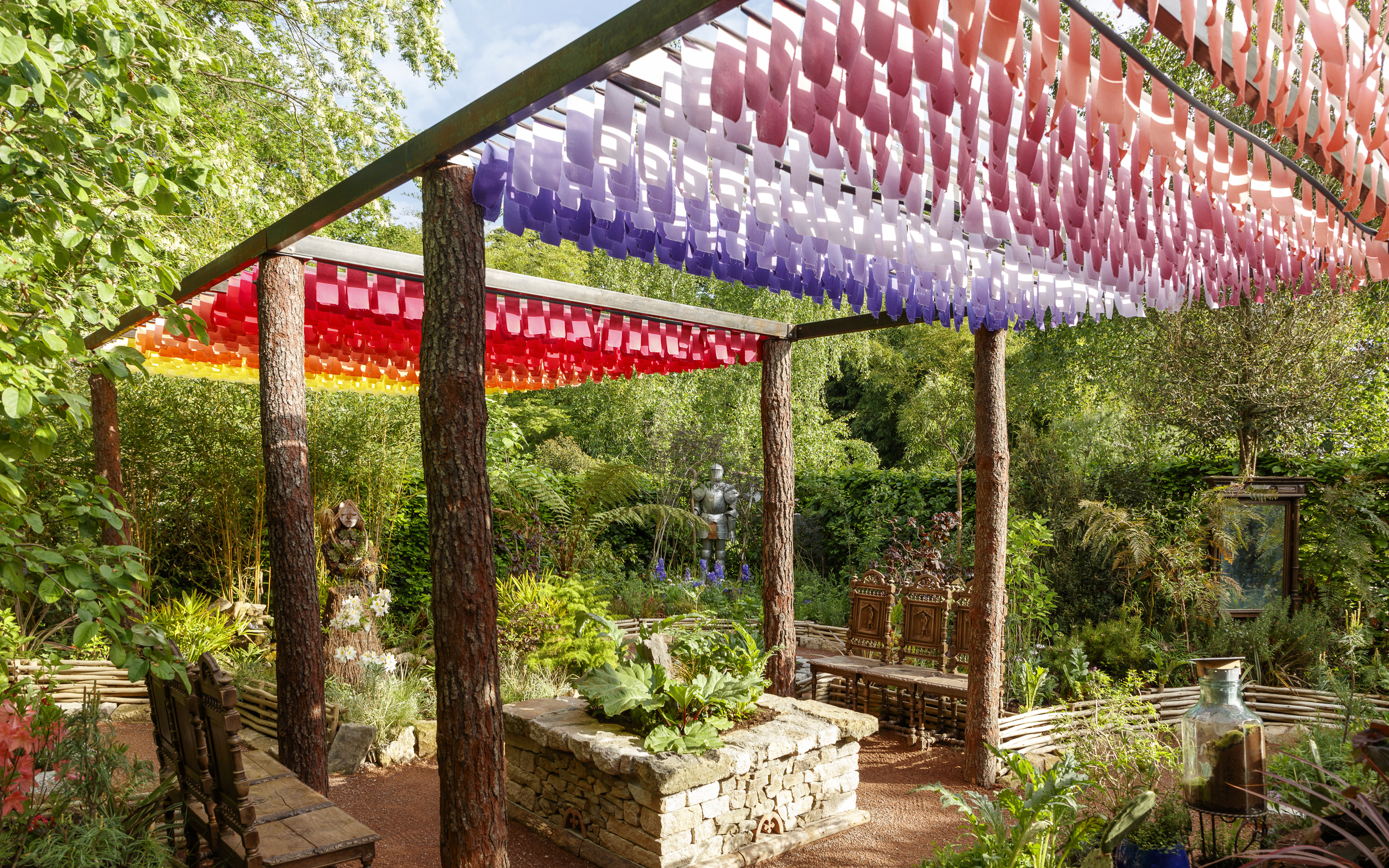Colorful canopy and garden at Chaumont-sur-Loire Castle, featuring lush greenery and a stone planter.