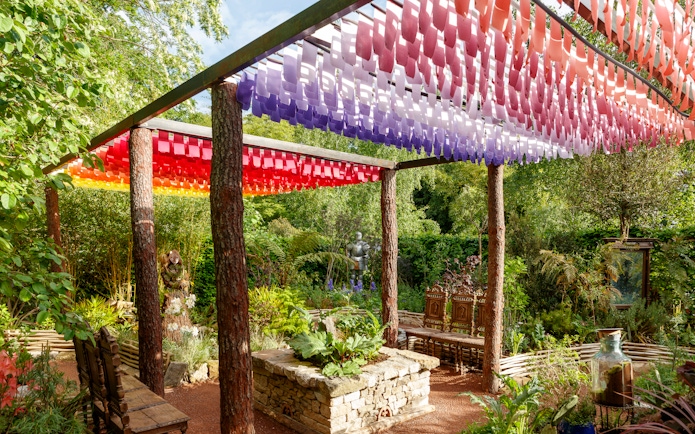 Colorful canopy and garden at Chaumont-sur-Loire Castle, featuring lush greenery and a stone planter.