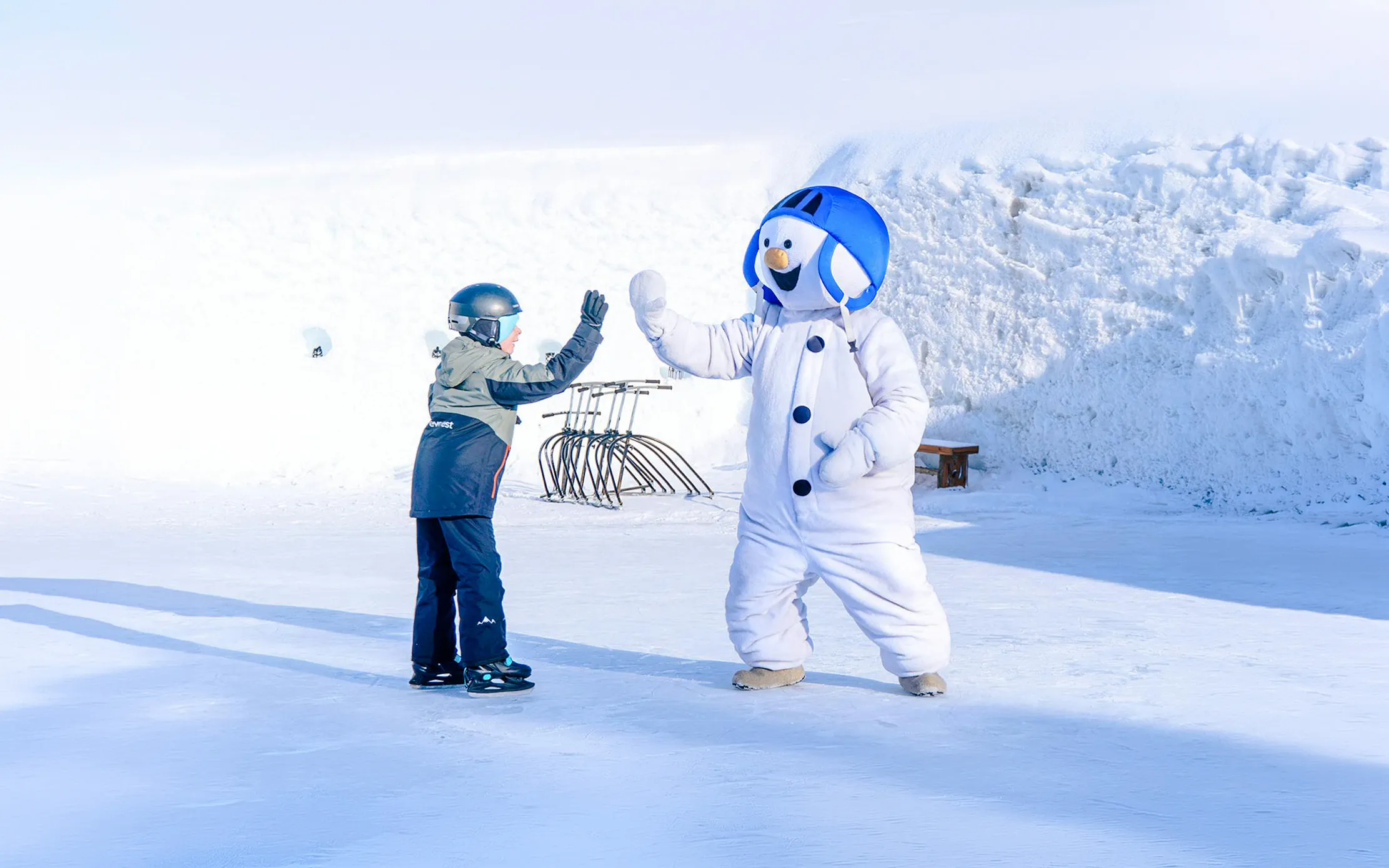Child high-fiving snowman character at Snowman World, Santa Claus Village.