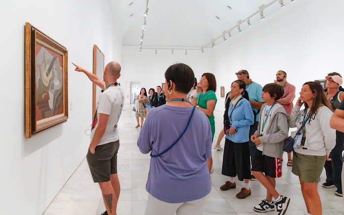 Visitors on a guided tour at Prado Museum viewing artwork.
