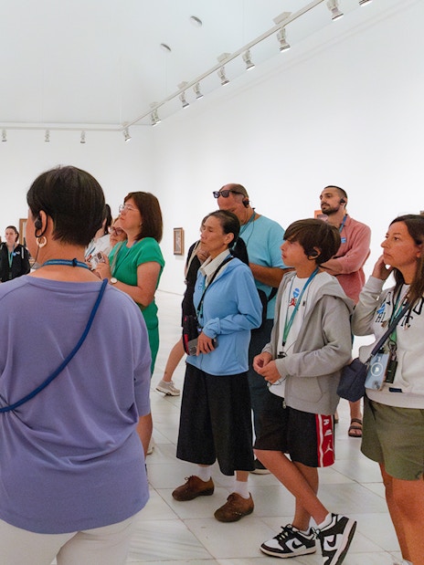 Visitors on a guided tour at Prado Museum viewing artwork.