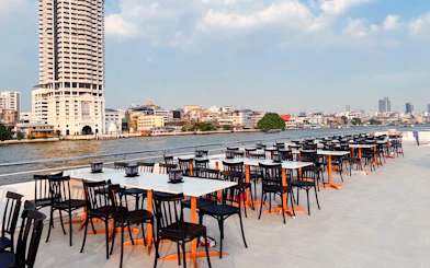 Outdoor dining tables on The Luxury White Dinner Cruise at ICONSIAM, Bangkok riverside view.