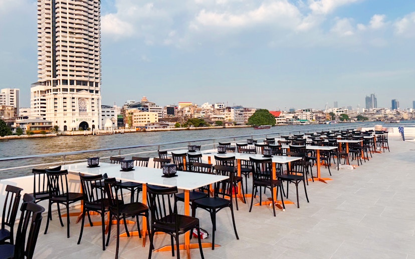 Outdoor dining tables on The Luxury White Dinner Cruise at ICONSIAM, Bangkok riverside view.