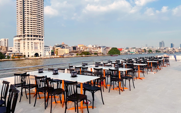 Outdoor dining tables on The Luxury White Dinner Cruise at ICONSIAM, Bangkok riverside view.