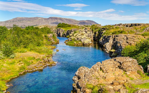 Rocky cliffs and lush greenery at Thingvellir National Park, Iceland.