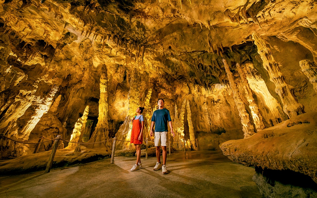 People exploring The Cavern in Rainforest Wild ASIA with stalactites and stalagmites.
