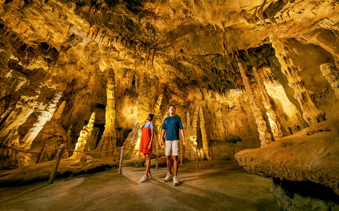People exploring The Cavern in Rainforest Wild ASIA with stalactites and stalagmites.