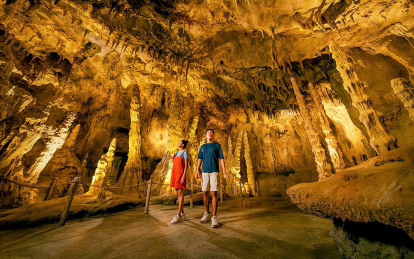 People exploring The Cavern in Rainforest Wild ASIA with stalactites and stalagmites.