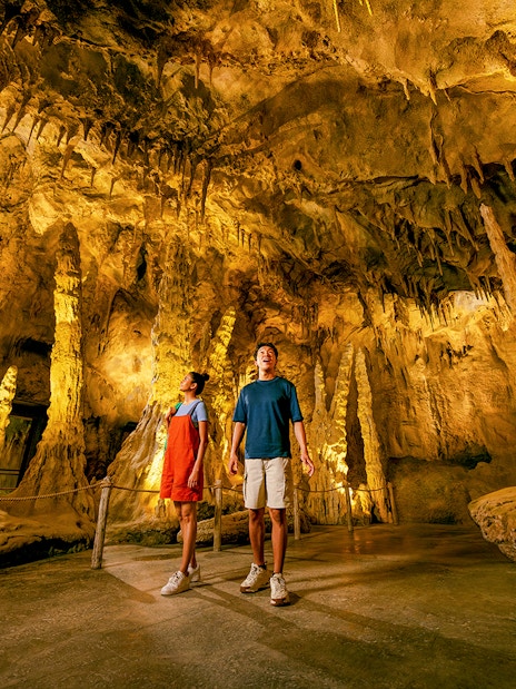 People exploring The Cavern in Rainforest Wild ASIA with stalactites and stalagmites.