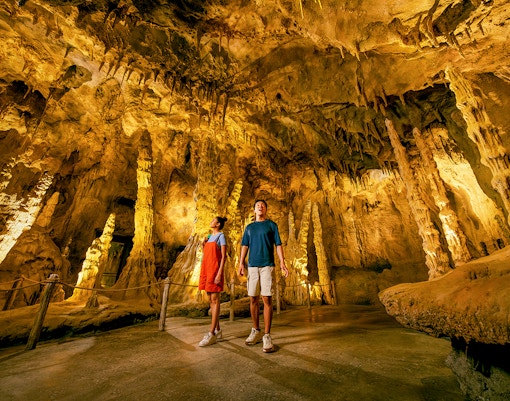 People exploring The Cavern in Rainforest Wild ASIA with stalactites and stalagmites.