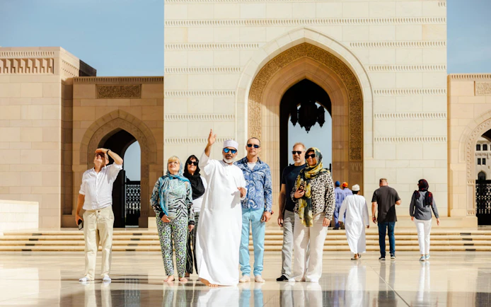 Guide with tourists at Royal Opera House entrance, Muscat.