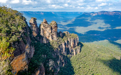 Three Sisters rock formation in Blue Mountains, Australia, surrounded by forest.