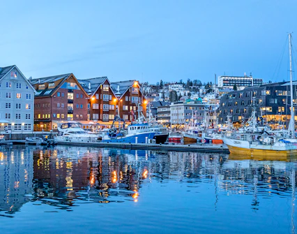 Boats docked at Tromso Harbour with colorful buildings in the background.