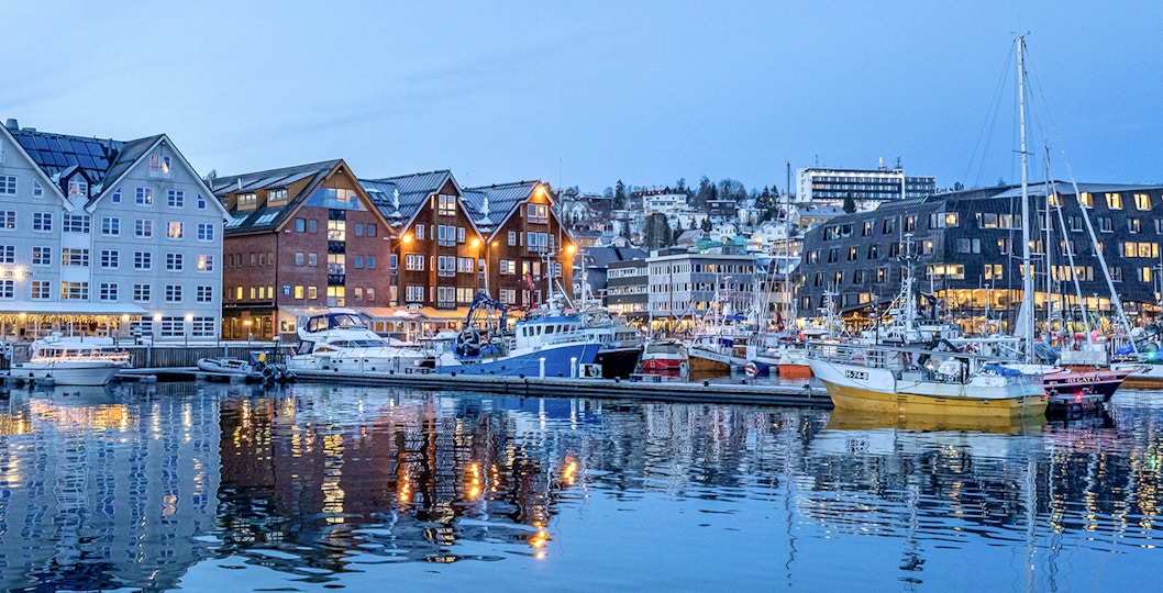 Boats docked at Tromso Harbour with colorful buildings in the background.