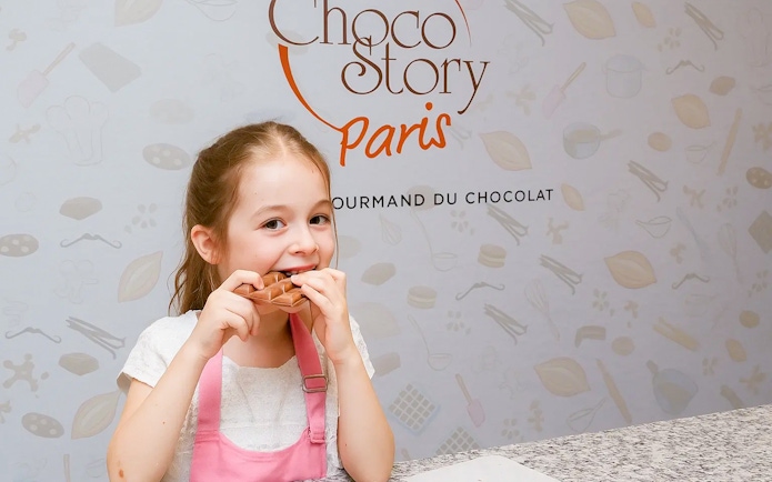 Child enjoying chocolate tasting at Choco-Story Museum, Paris.