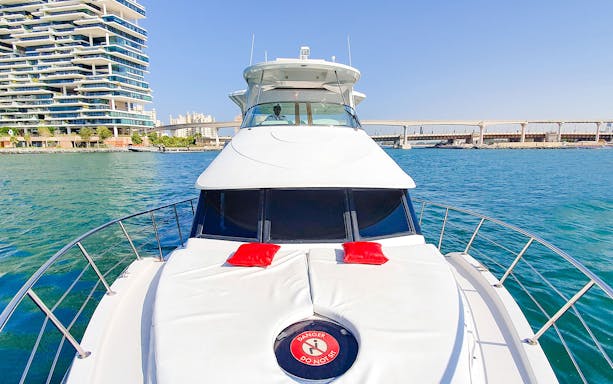 Luxury yacht cruising near Dubai Marina with modern buildings in the background.