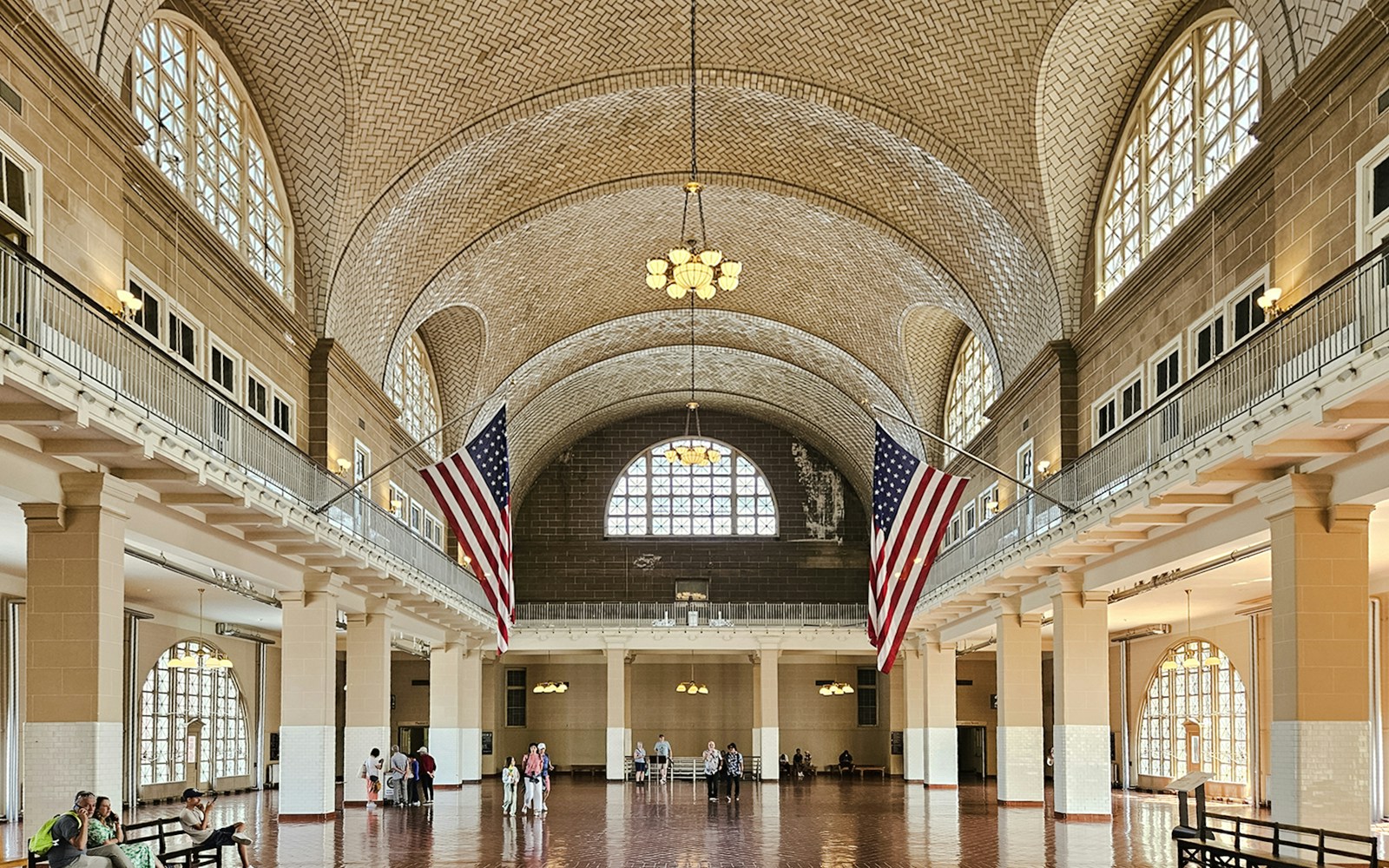 Wide-angle view of the Great Hall interior at Ellis Island National Museum of Immigration, featuring American flags.