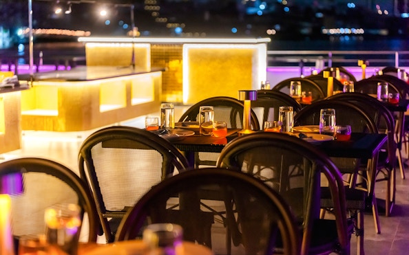 Dining setup on Bangkok Chaophraya Cruise with tables and ambient lighting.