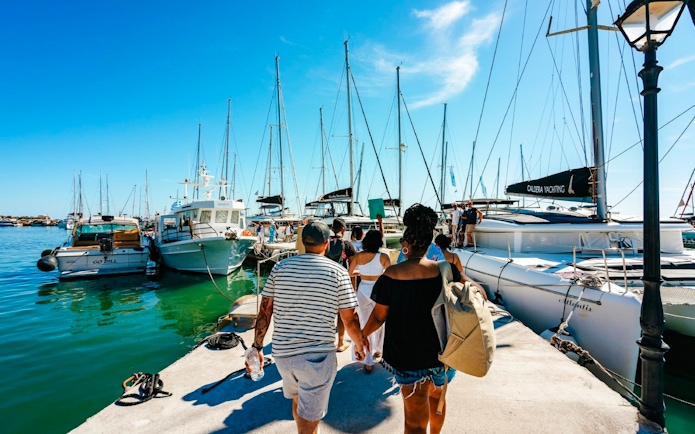 Guests boarding a catamaran for a classic cruise at a marina.