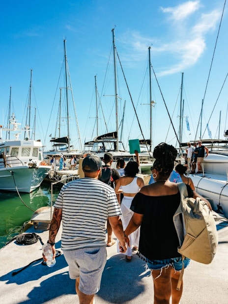 Guests boarding a catamaran for a classic cruise at a marina.