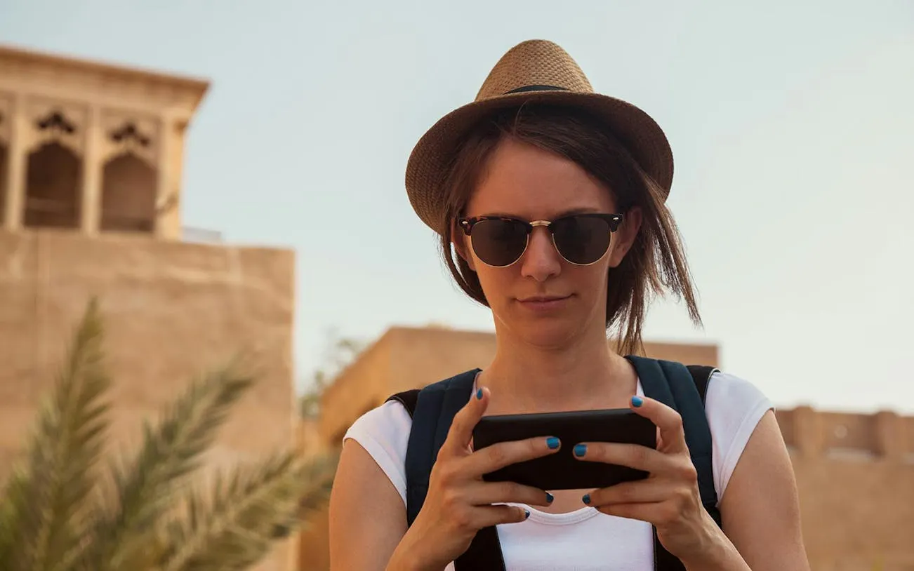 Tourist using smartphone for self-guided exploration in Old Dubai.