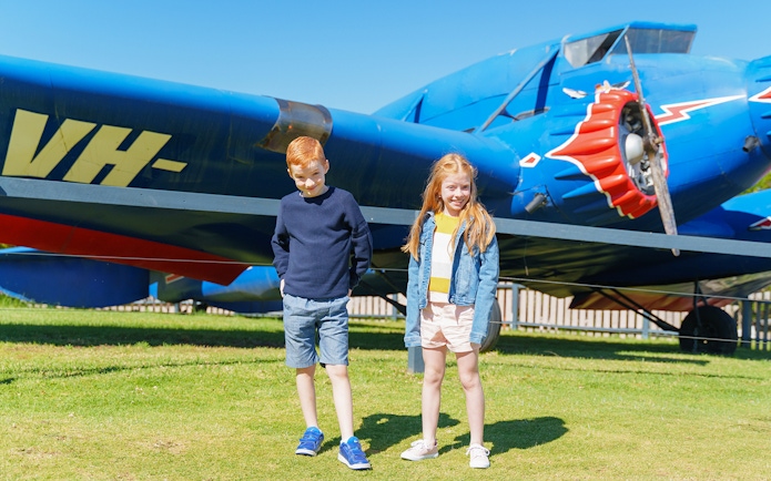 Children in front of vintage blue aircraft at O'Reilly's Rainforest Retreat.
