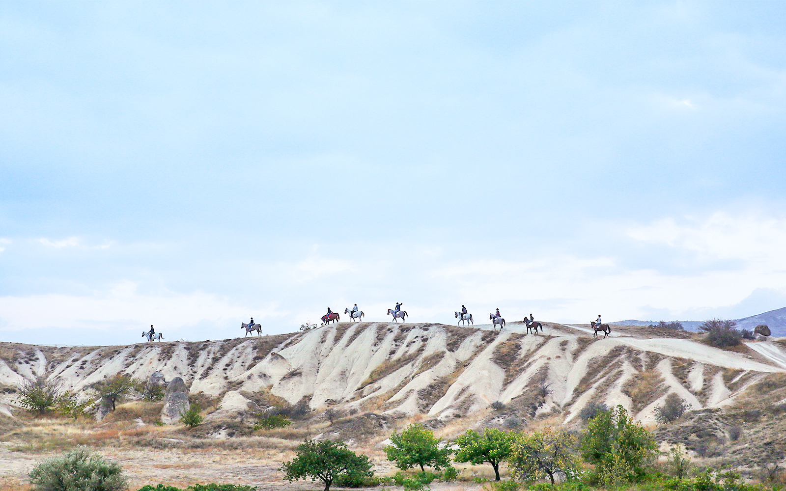 Group horseback riding on Cappadocia's unique landscape, Turkey.