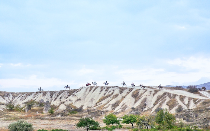 Group horseback riding on Cappadocia's unique landscape, Turkey.