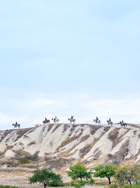 Group horseback riding on Cappadocia's unique landscape, Turkey.