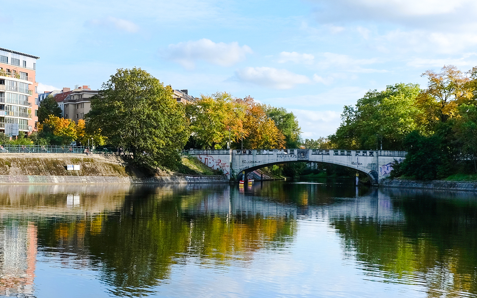Lohmühlen Bridge over the Landwehr Canal in Berlin with autumn trees reflecting in the water.