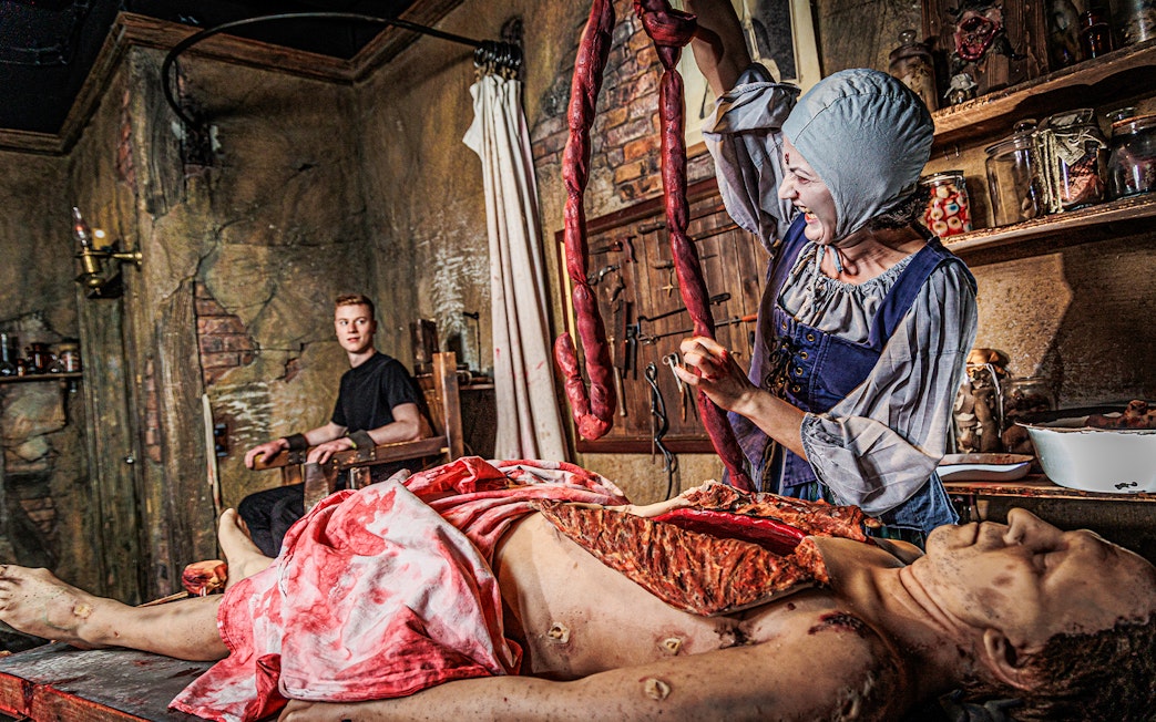Actor in period costume performing surgery scene at London Dungeon.