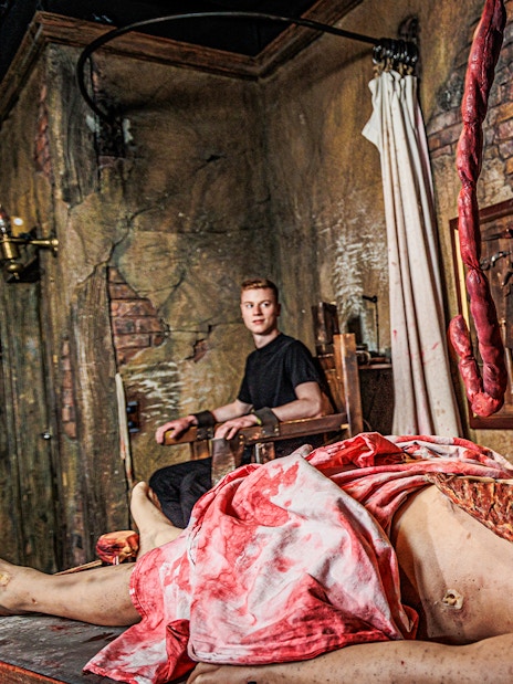 Actor in period costume performing surgery scene at London Dungeon.