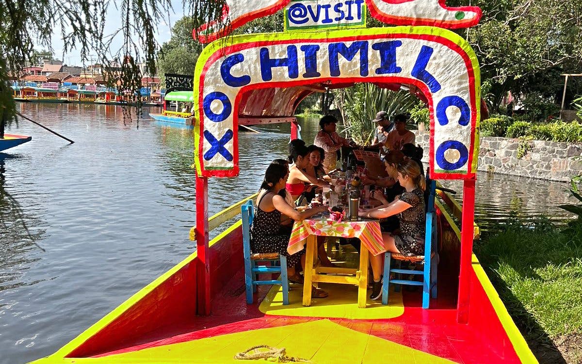Trajinera boat with people enjoying drinks on Xochimilco canals, Mexico City.