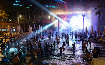 Crowd enjoying a night pool party with lights at Aquaventure After Dark.