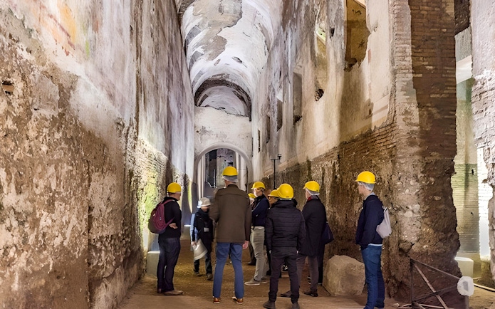 Visitors with helmets exploring Domus Aurea's ancient corridors in Rome.