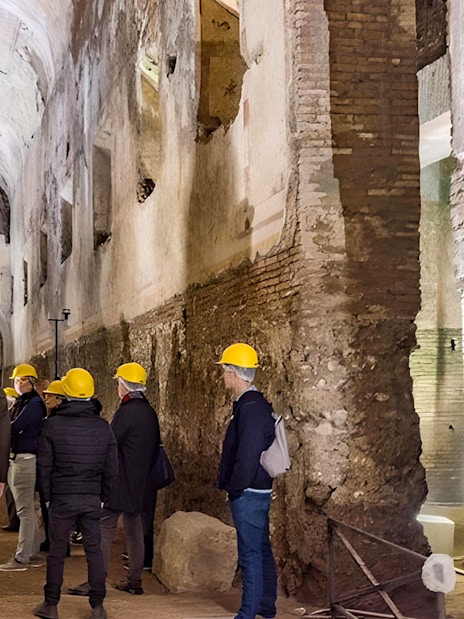 Visitors with helmets exploring Domus Aurea's ancient corridors in Rome.