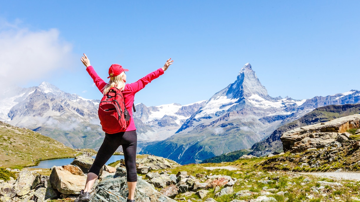 Hiker with arms raised facing the Matterhorn from Gornergrat, Switzerland.