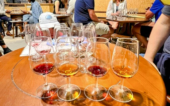 Guests seated at tables enjoying a wine tasting experience with glasses of red and white wine.