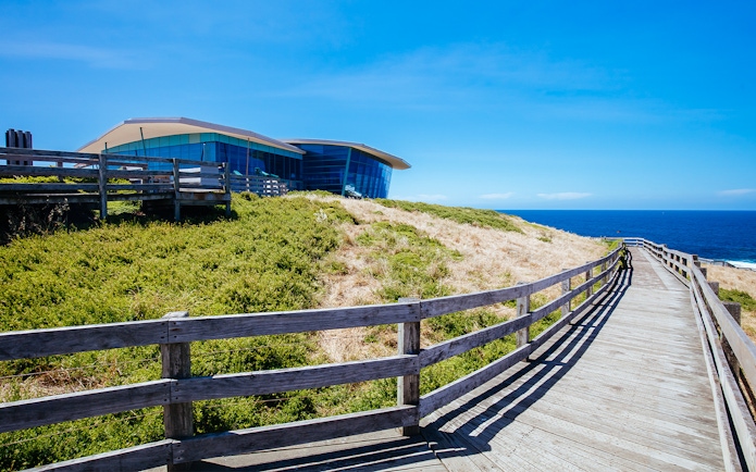Coastal boardwalk leading to modern building on Phillip Island, Australia.