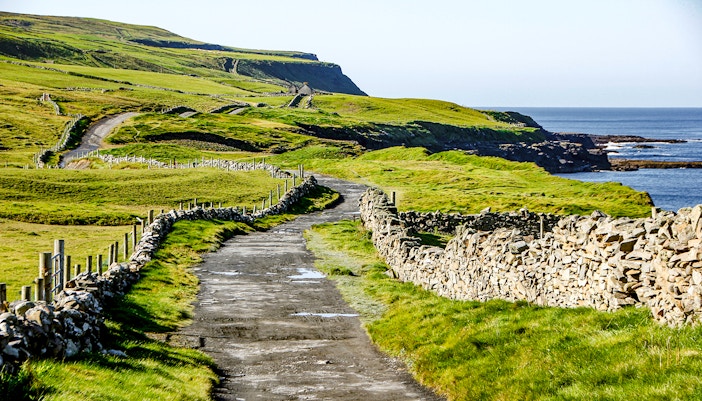 Footpath from Doolin to Cliffs of Moher with stone walls and ocean view.