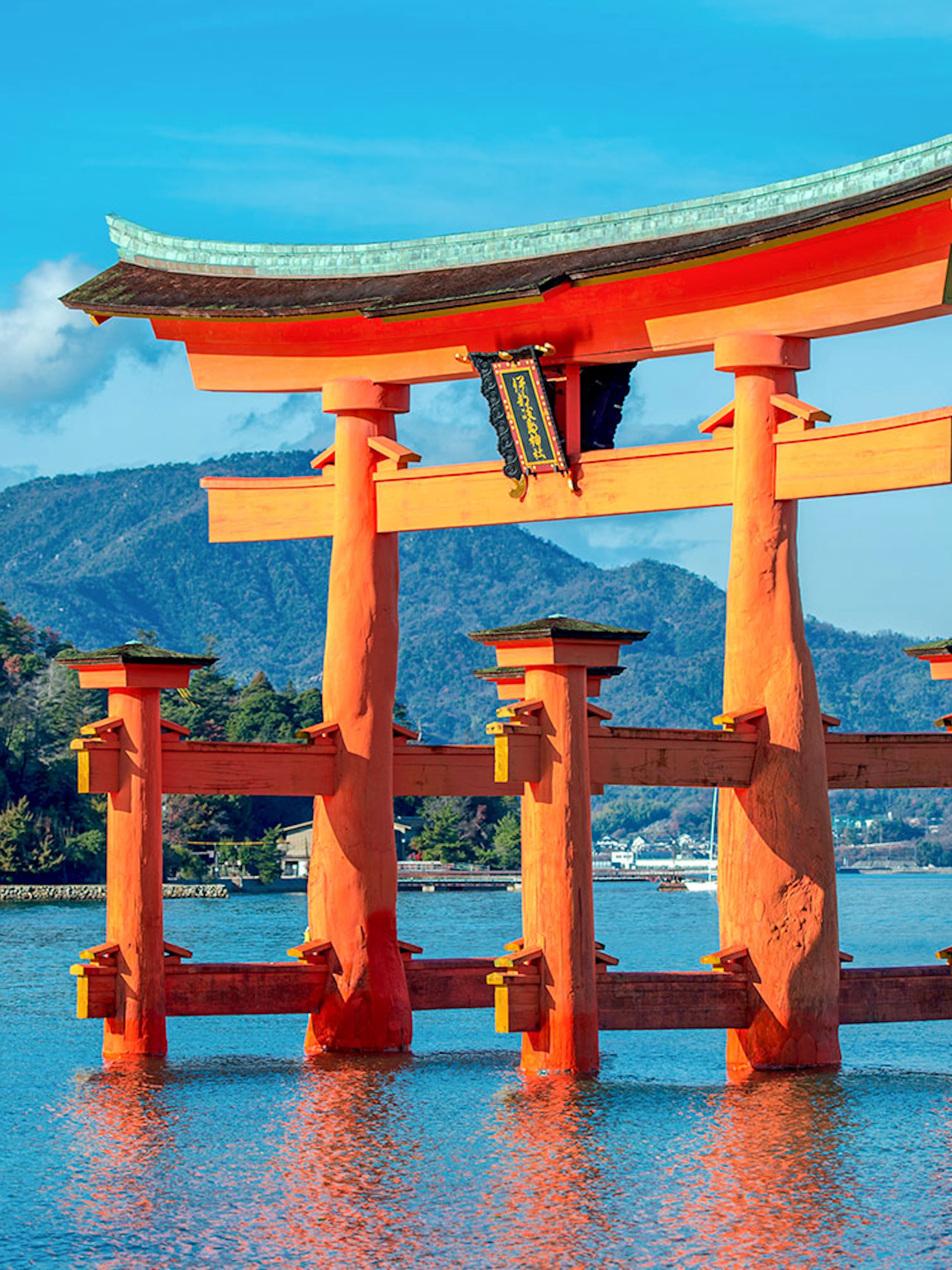 Torii gate at Itsukushima Shrine, Miyajima, Japan, with mountains in the background.